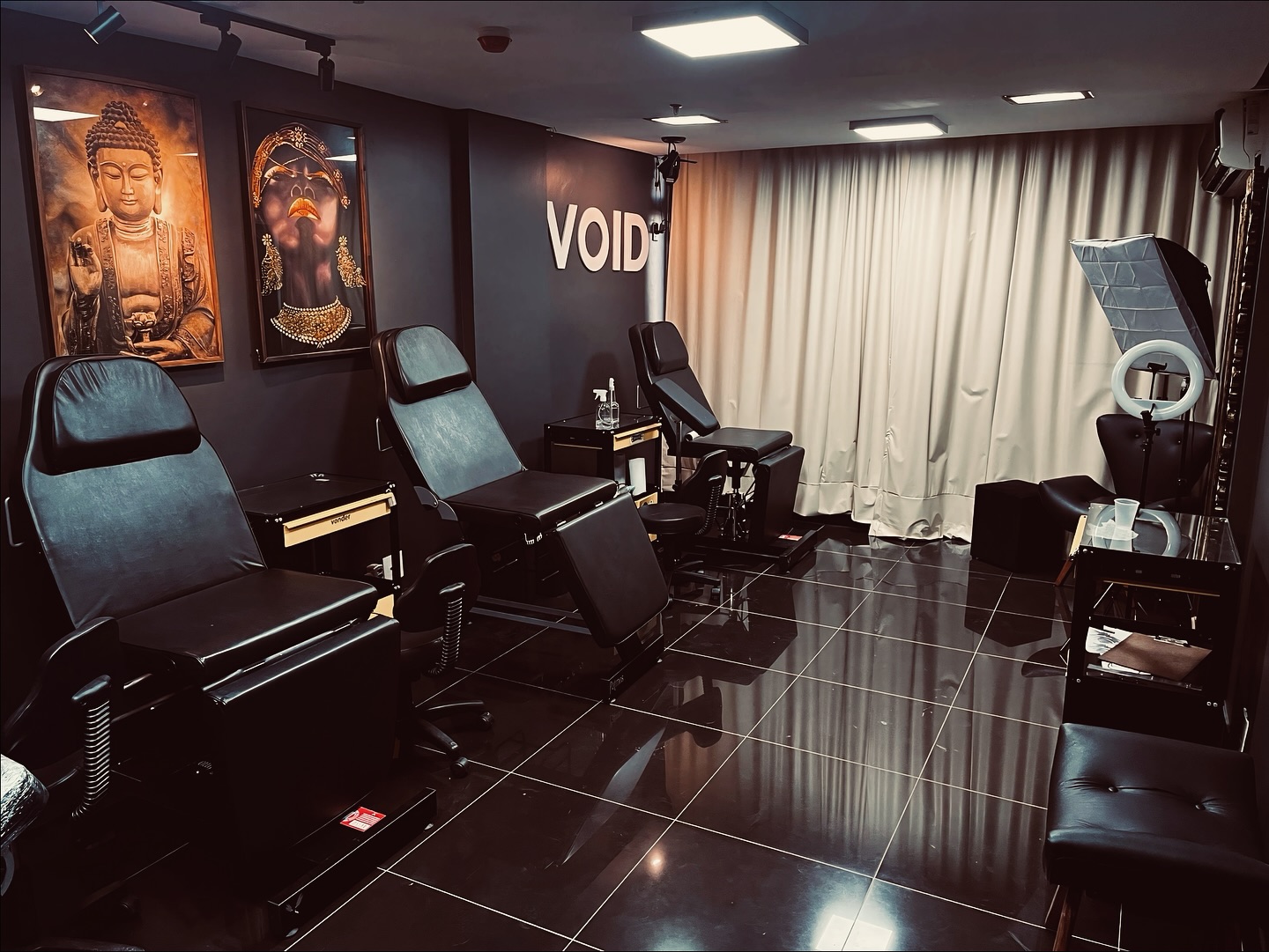 Sala de atendimento do estúdio Fiorge Tattoo, com macas pretas, iluminação suave e quadros na parede